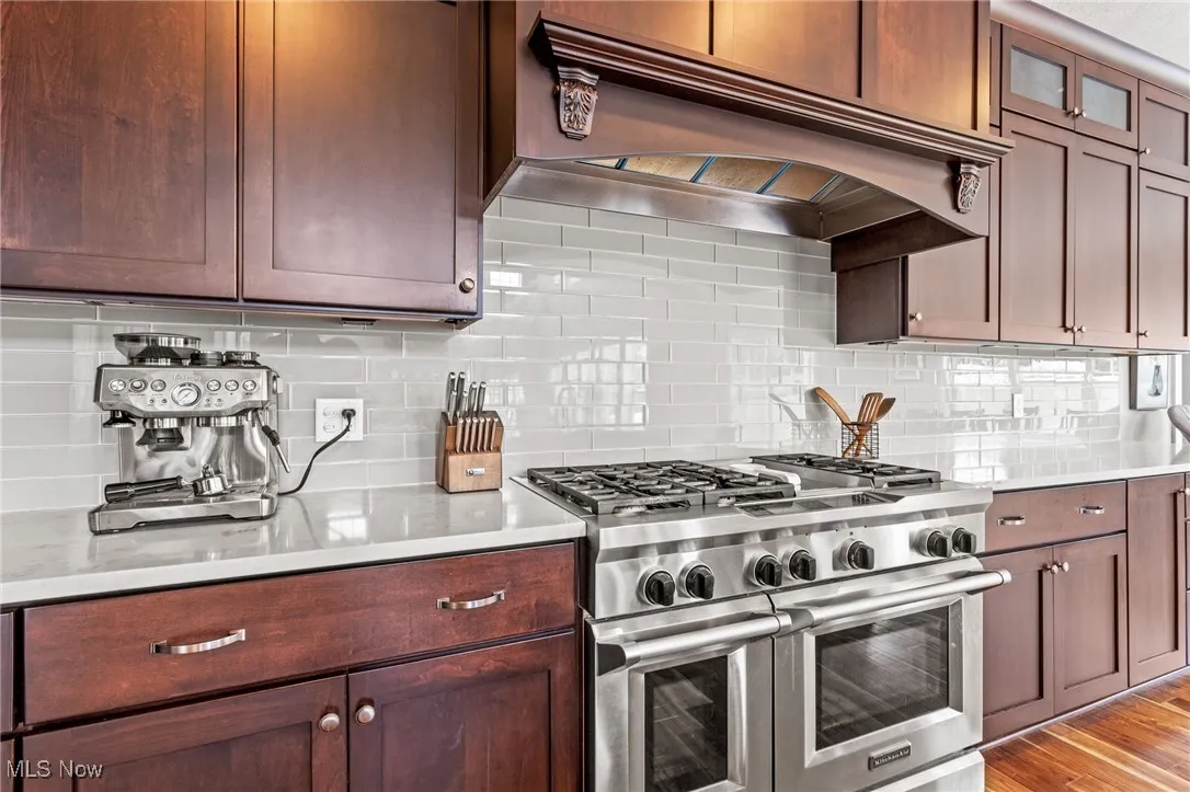Kitchen featuring custom range hood, range with two ovens, light countertops, and tasteful backsplash