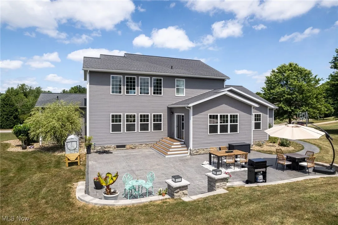 Back of property featuring a patio, a yard, and a shingled roof