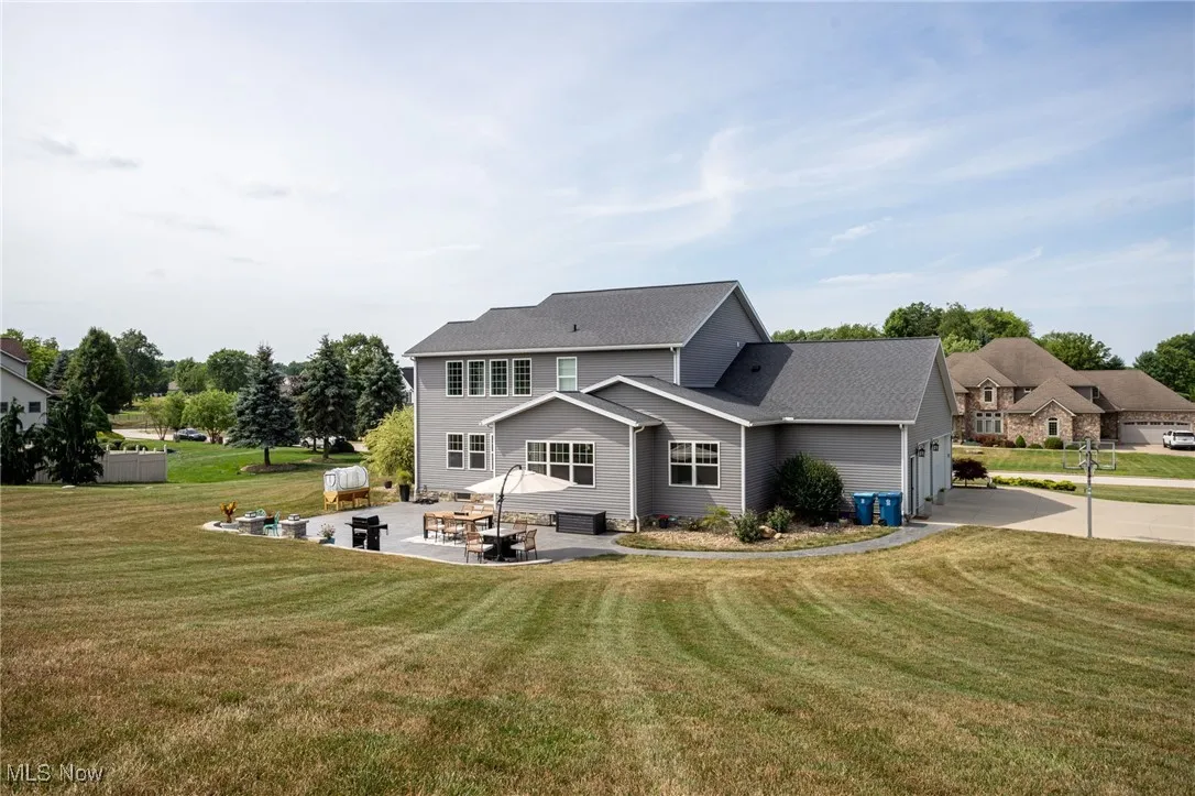 Back of property with a yard, concrete driveway, and a patio