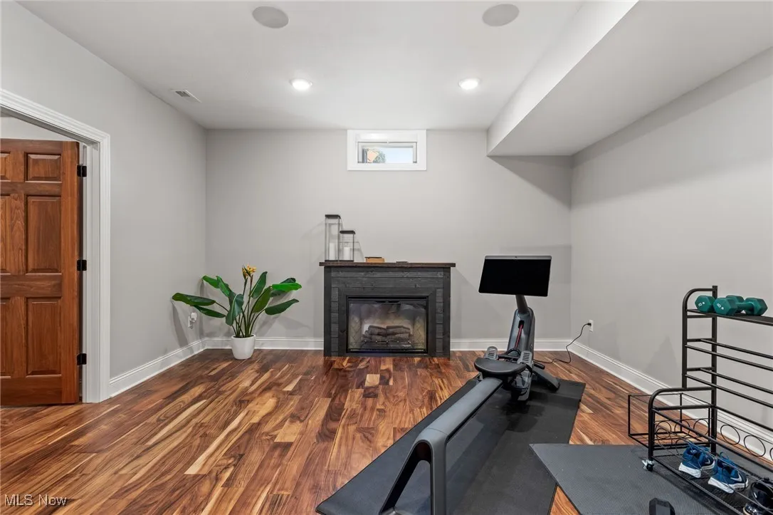 Exercise room featuring wood finished floors, a glass covered fireplace, and recessed lighting