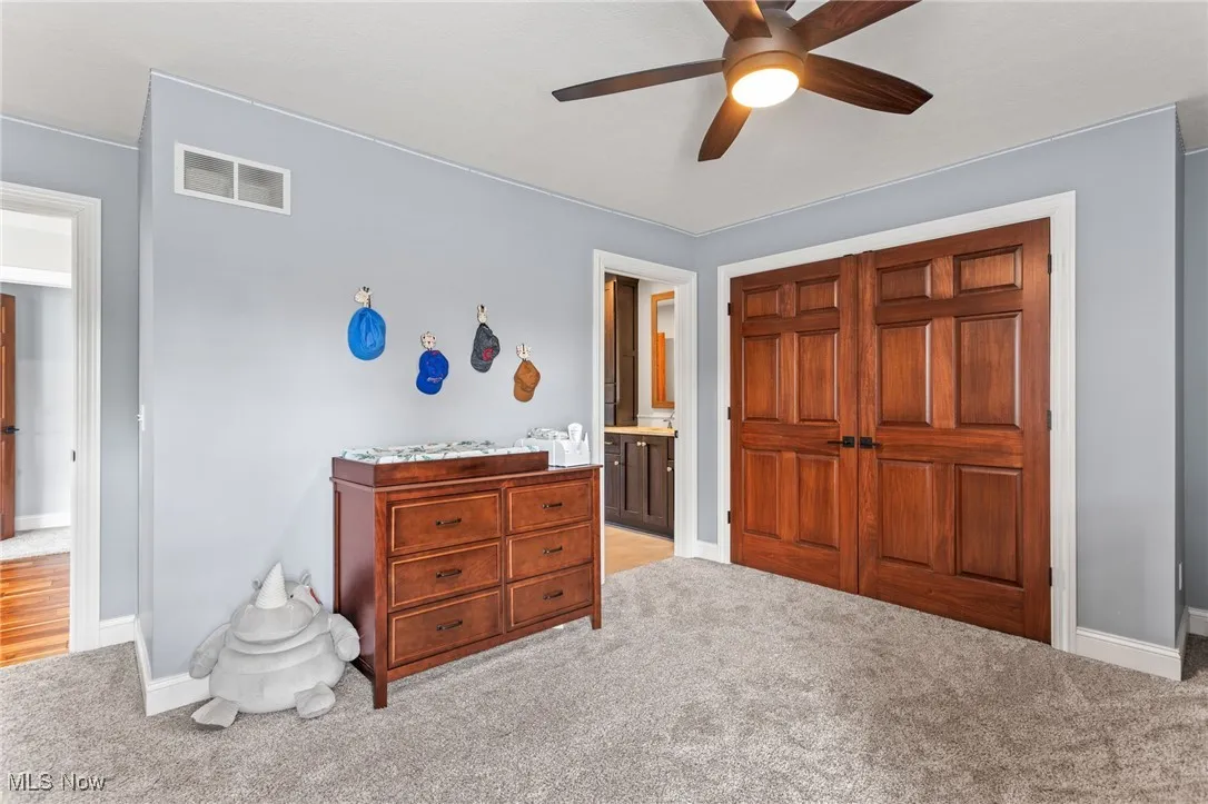 Bedroom featuring carpet floors, connected bathroom, and a ceiling fan