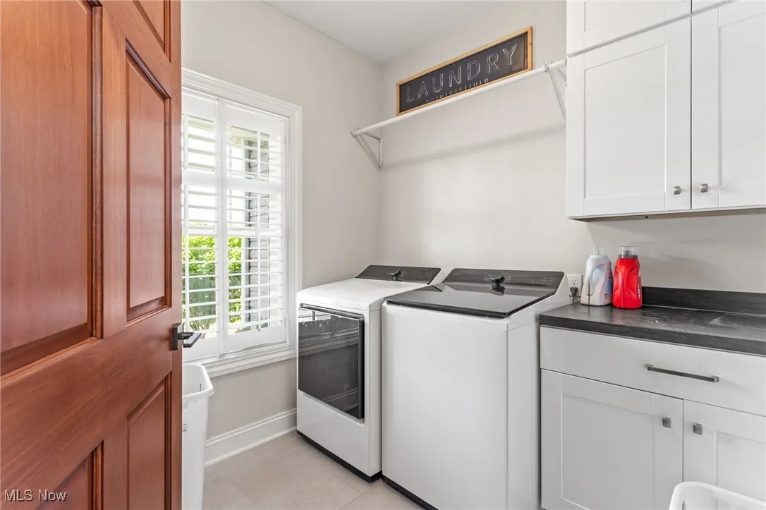 Laundry area with washer and dryer, cabinet space, and light tile patterned floors