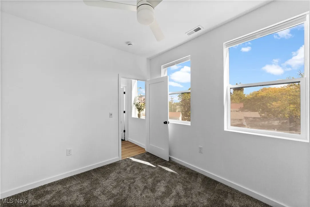 Carpeted spare room with ceiling fan and baseboards