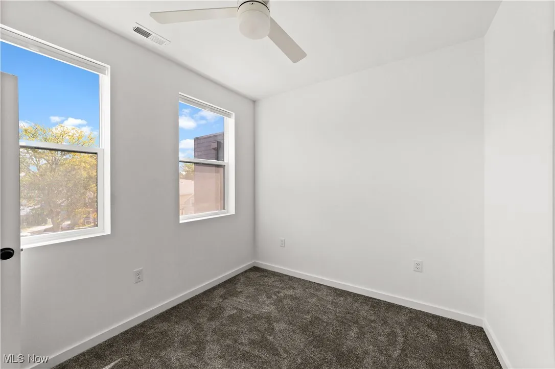 Unfurnished room featuring dark carpet and a ceiling fan