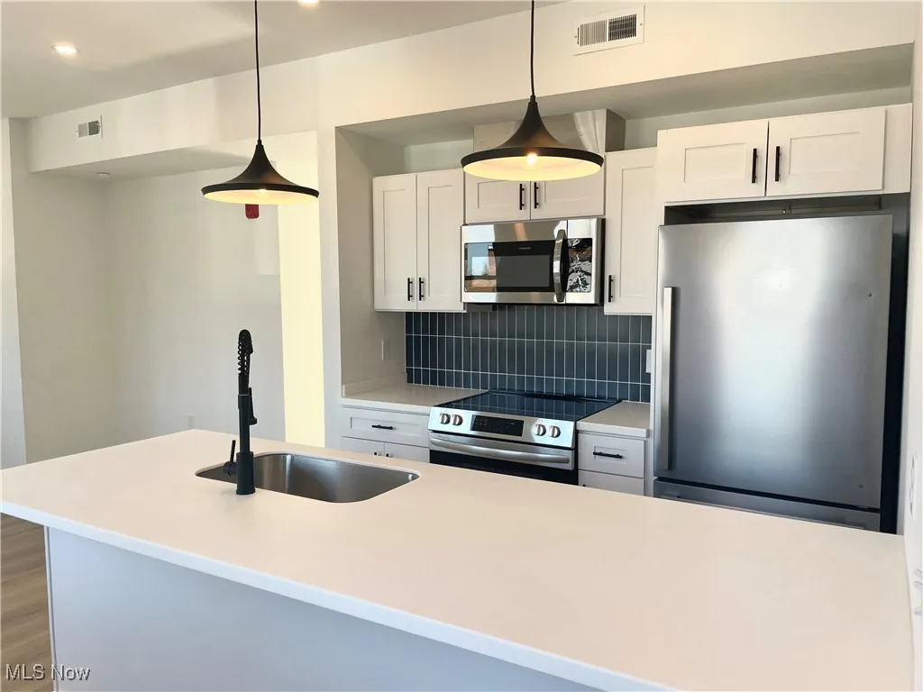 Kitchen featuring appliances with stainless steel finishes, backsplash, white cabinetry, recessed lighting, and light countertops