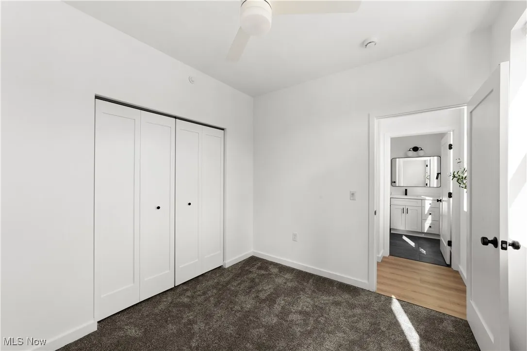 Unfurnished bedroom with carpet, a closet, and a ceiling fan