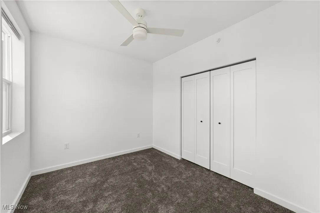 Unfurnished bedroom featuring carpet, a closet, and a ceiling fan