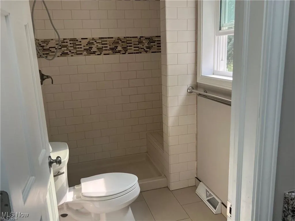Full bath with a shower stall and tile patterned flooring