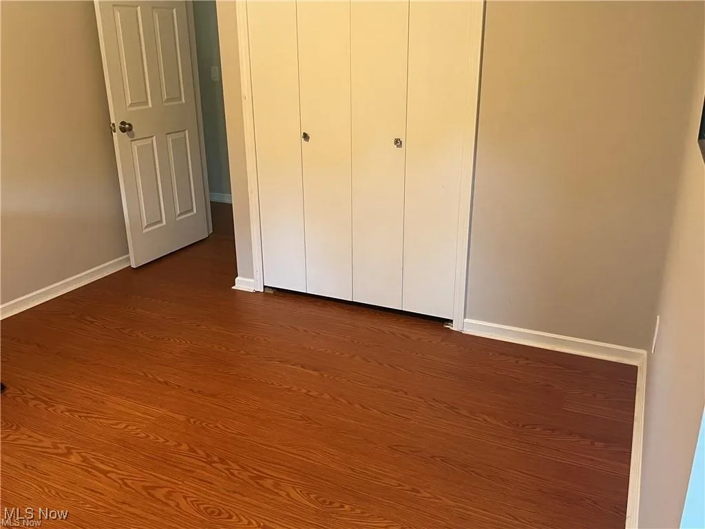 Unfurnished bedroom featuring dark wood-style floors and a closet