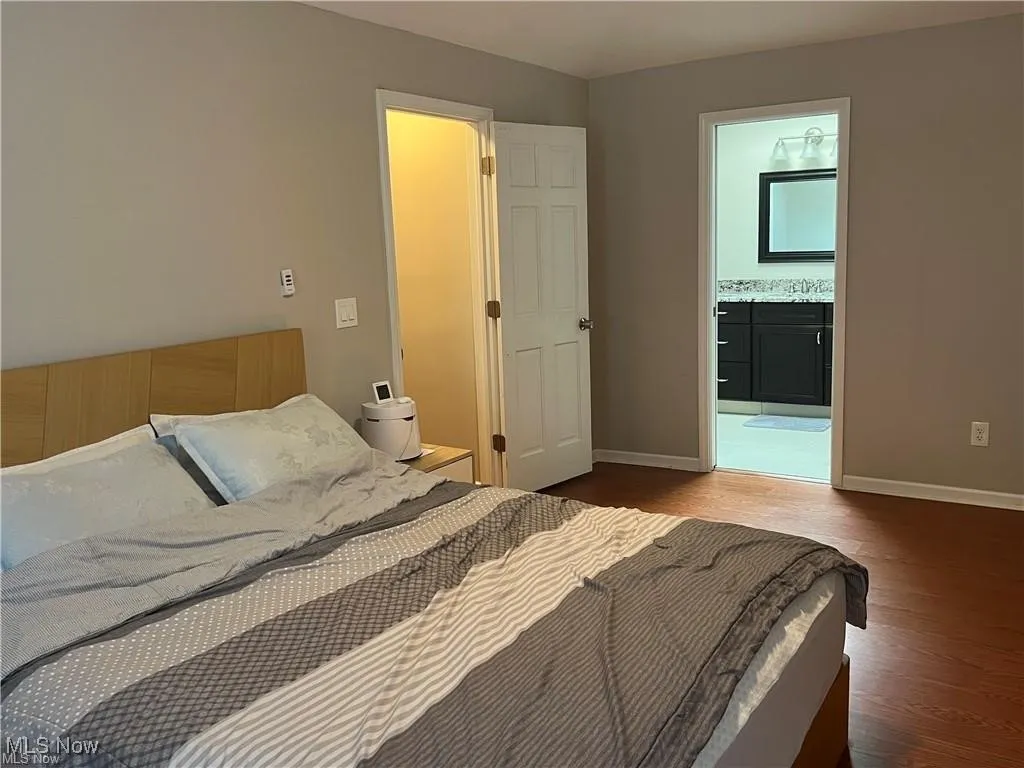 Bedroom with dark wood-type flooring and connected bathroom
