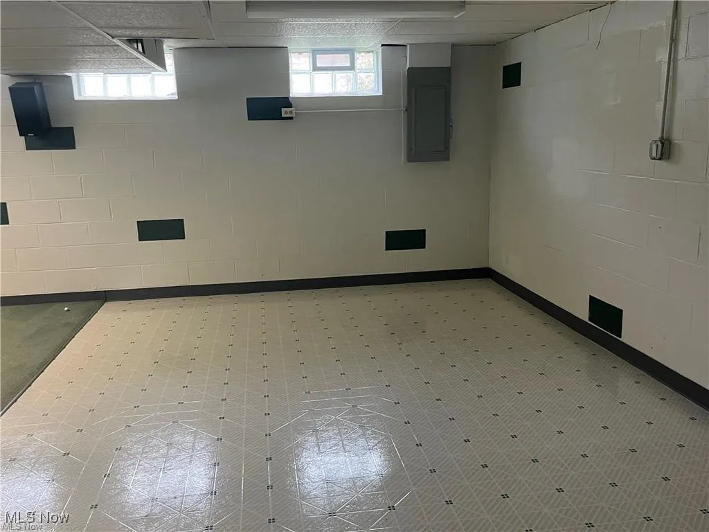 Basement featuring electric panel and concrete block wall