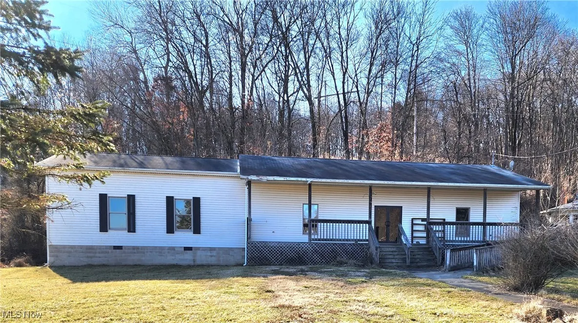 View of front of house featuring a front lawn and a wooden deck