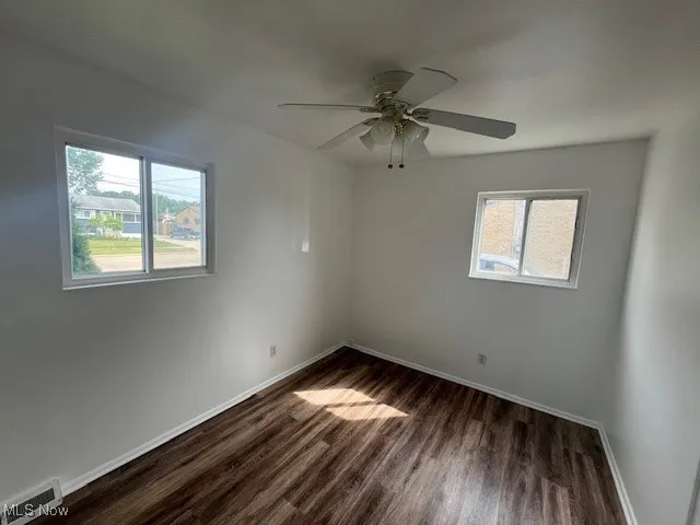 Empty room featuring dark wood finished floors and ceiling fan