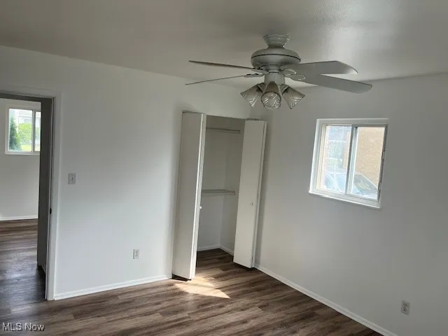 Unfurnished bedroom with a closet, dark wood finished floors, and a ceiling fan