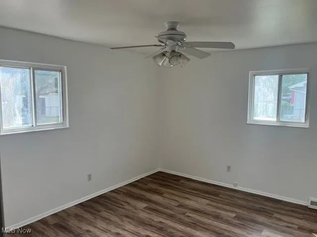 Empty room featuring dark wood finished floors and a ceiling fan