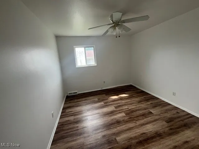 Spare room with a ceiling fan and dark wood-type flooring