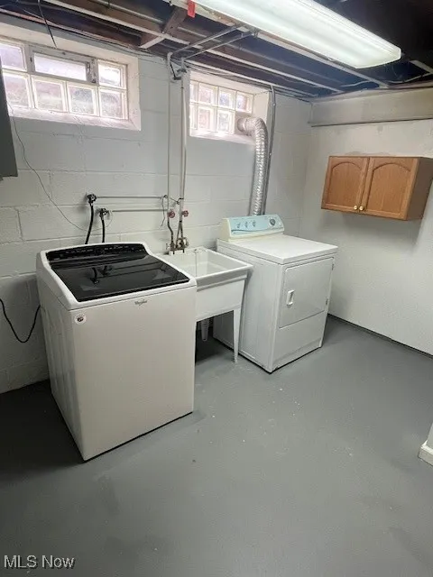 Laundry area with washing machine and dryer, plenty of natural light, and concrete block wall