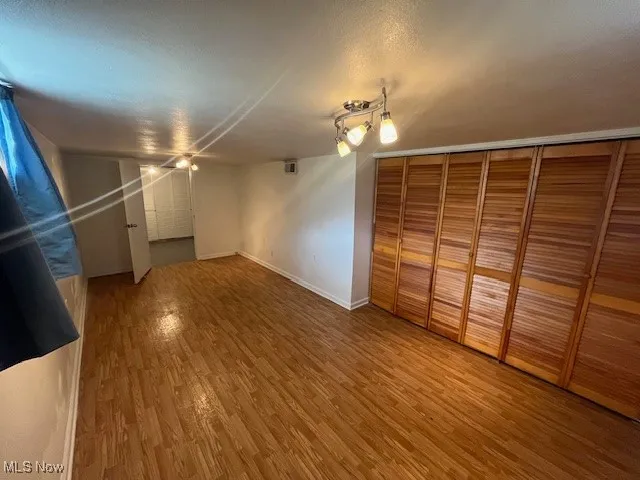 Unfurnished bedroom with wood finished floors and a closet