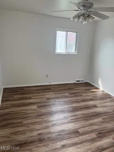 Unfurnished room with a ceiling fan and dark wood-type flooring