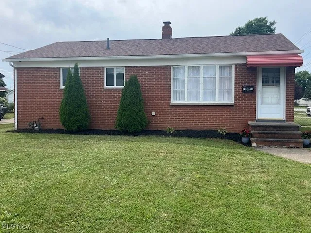 Ranch-style home with a front lawn, brick siding, a chimney, and entry steps