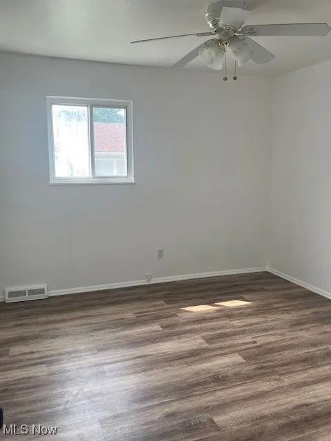 Spare room with dark wood-type flooring and a ceiling fan