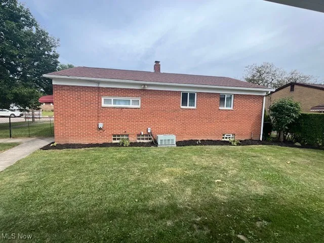 Rear view of house featuring a chimney and brick siding