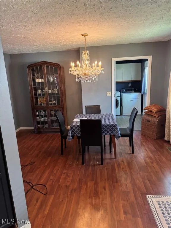 Dining space featuring washing machine and clothes dryer, a chandelier, wood finished floors, and a textured ceiling