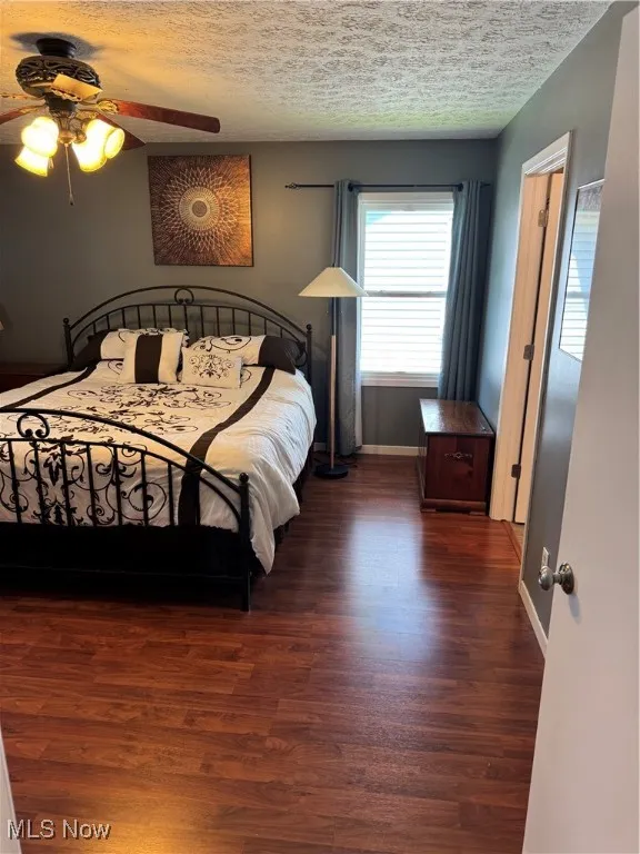 Bedroom with wood finished floors, a textured ceiling, and ceiling fan