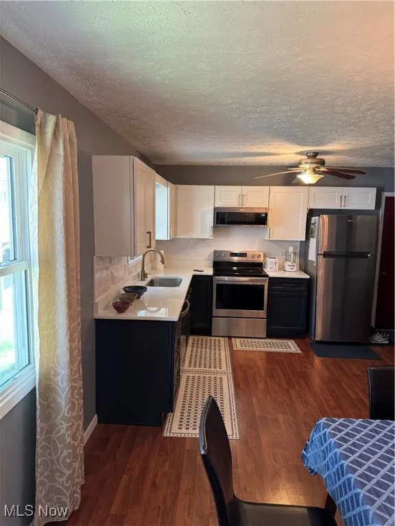 Kitchen featuring range with electric cooktop, light countertops, fridge, dark wood finished floors, and a textured ceiling