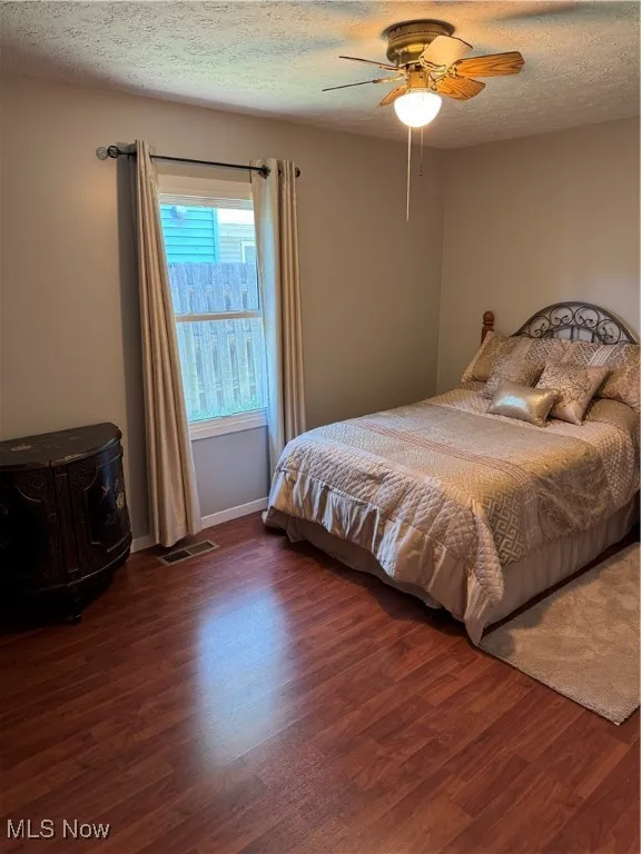 Bedroom featuring wood finished floors, a ceiling fan, and a textured ceiling