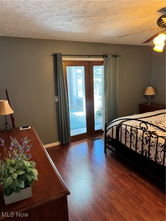 Bedroom featuring access to outside, dark wood finished floors, a textured ceiling, and a ceiling fan