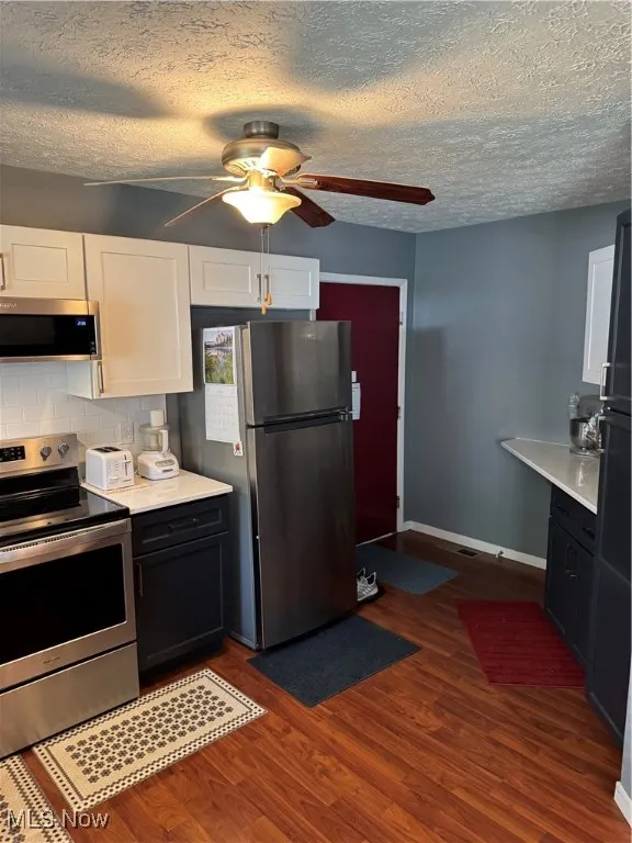 Kitchen featuring range, ceiling fan, light countertops, dark wood-style flooring, and a textured ceiling