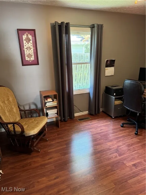 Bedroom with a wood stove, wood finished floors, a textured ceiling, a closet, and a ceiling fan
