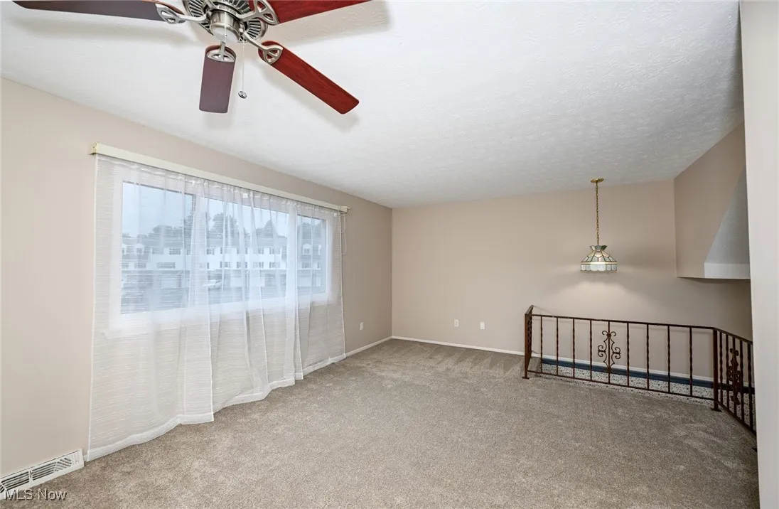 Empty room featuring carpet and ceiling fan