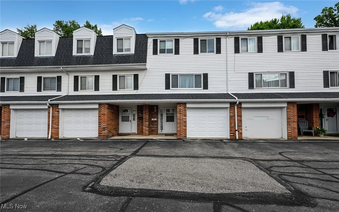 View of front of house featuring brick siding, an attached garage, roof with shingles, and driveway