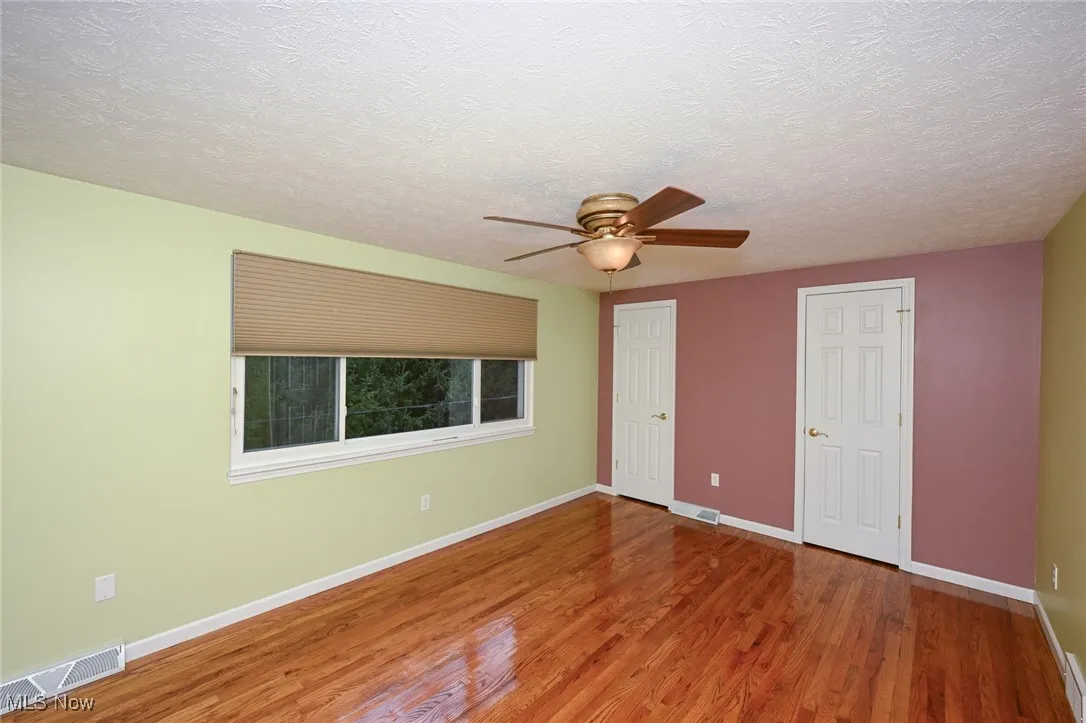 Unfurnished bedroom featuring wood finished floors, a textured ceiling, and ceiling fan
