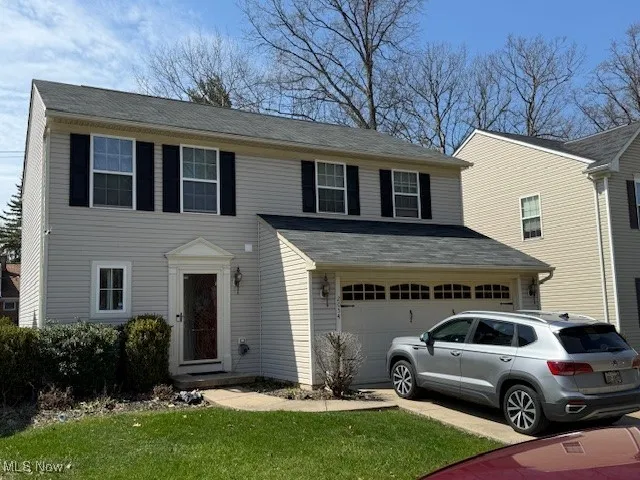 View of front of home featuring an attached garage, driveway, and a front lawn