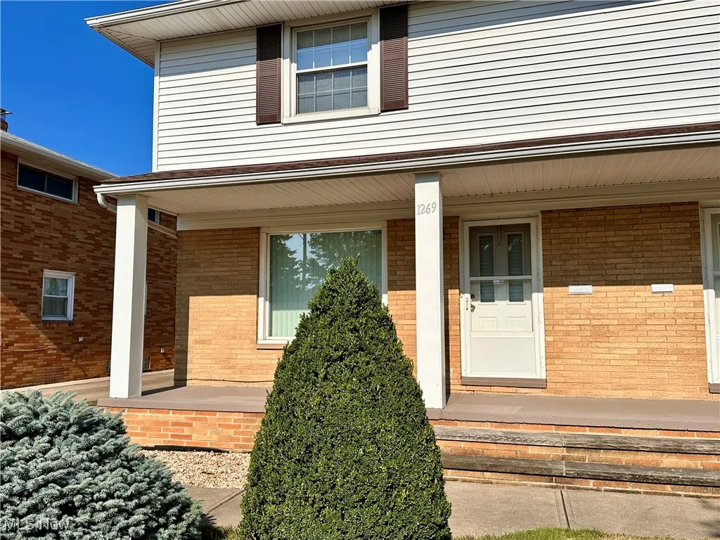 View of exterior entry featuring a porch and brick siding