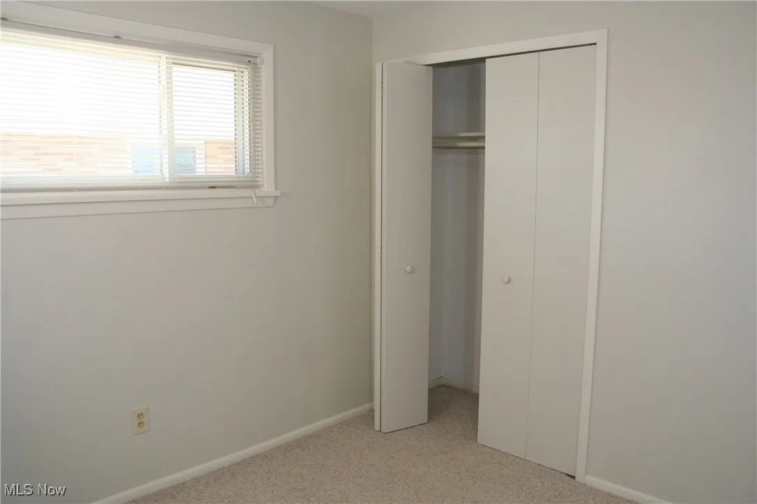 Unfurnished bedroom with light colored carpet and a closet