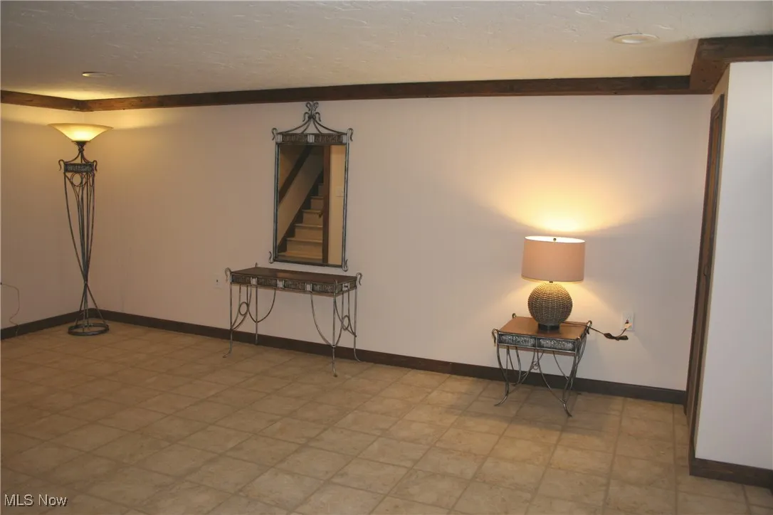 Empty room with a textured ceiling, stairs, and light floors