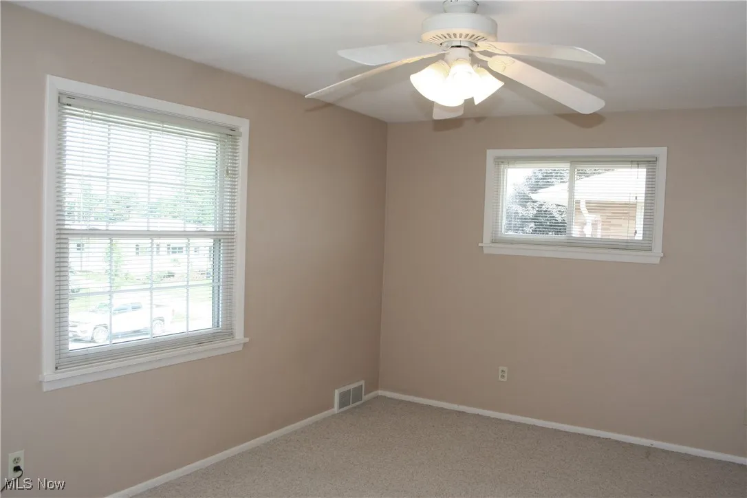 Unfurnished room with plenty of natural light, light carpet, and a ceiling fan