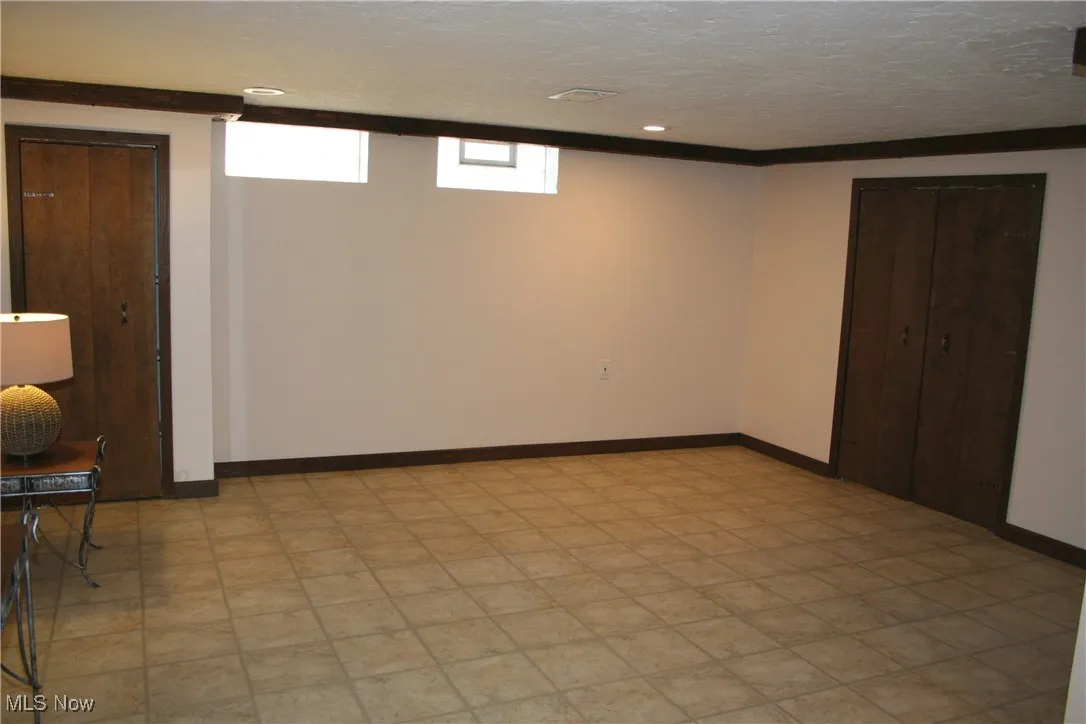 Below grade area with light floors, recessed lighting, and a textured ceiling