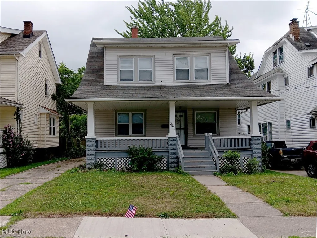 View of front facade featuring covered porch, a front yard, and a shingled roof