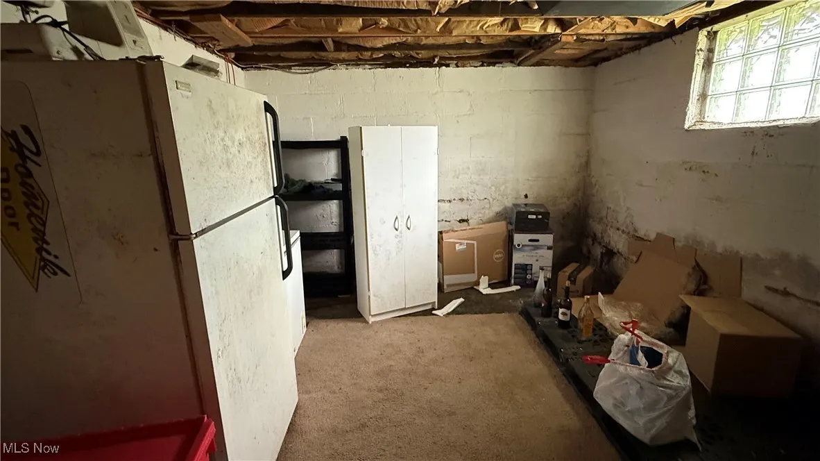 Below grade area featuring freestanding refrigerator