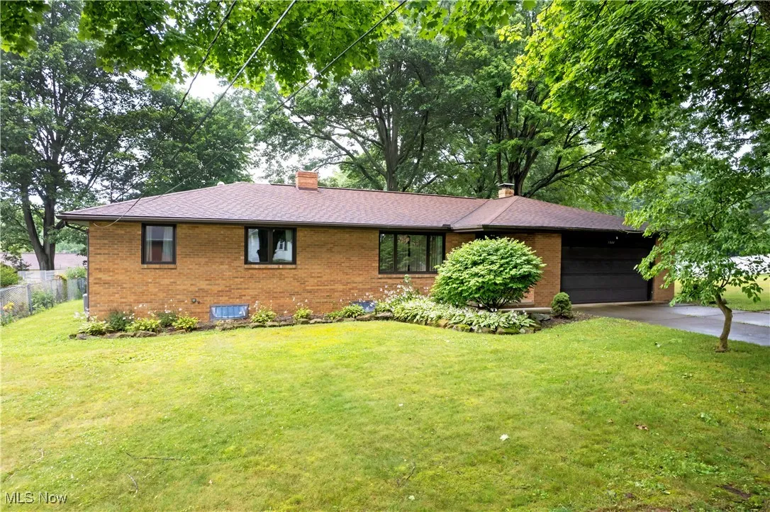 View of front of property featuring a chimney, brick siding, concrete driveway, a garage, and a shingled roof