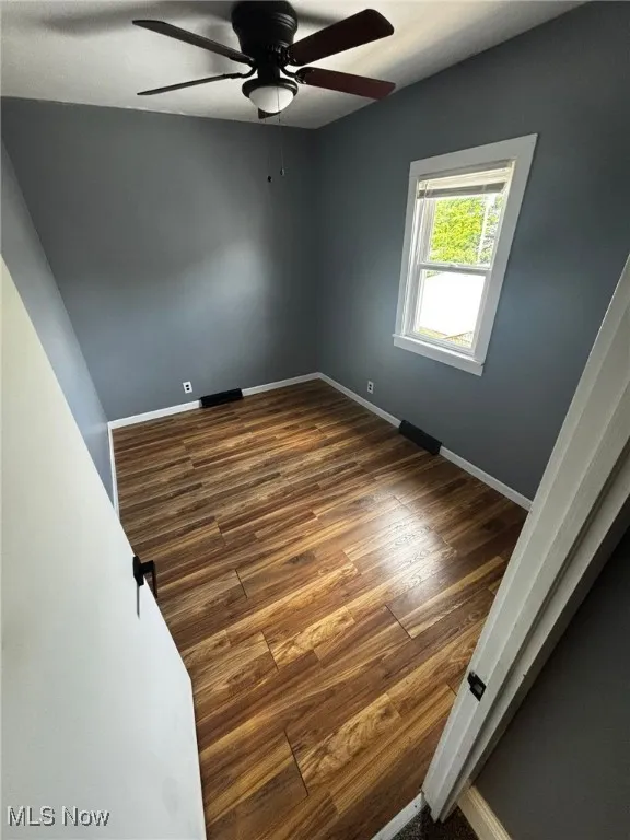 Unfurnished room featuring ceiling fan and dark wood-style floors