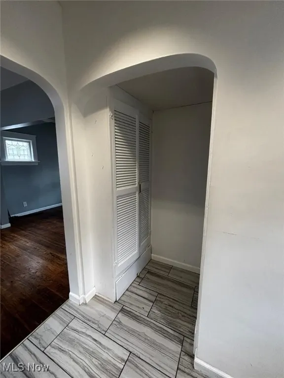 Hallway featuring arched walkways and baseboards