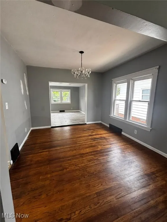 Spare room with wood finished floors and a chandelier