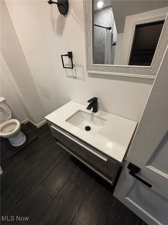 Full bathroom with vanity, a tile shower, and wood finished floors