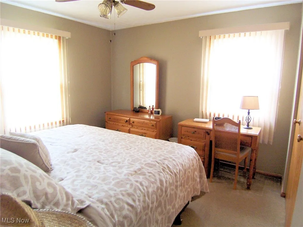 Bedroom featuring light carpet, ornamental molding, and ceiling fan